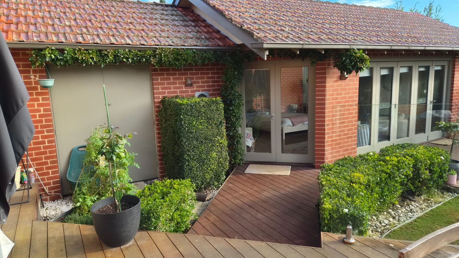 Trimmed courtyard hedges at a deck entrance, garden maintenance in Bayside Melbourne