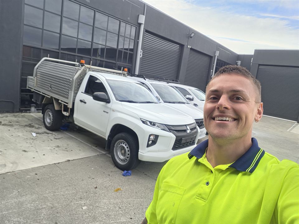 Stephen Wilson, owner of Wilson's Mowing, in a hi-vis work shirt beside his ute